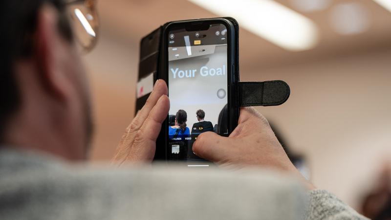 At NEXTWAVE a man takes a photo of a screen that says YOUR GOAL
