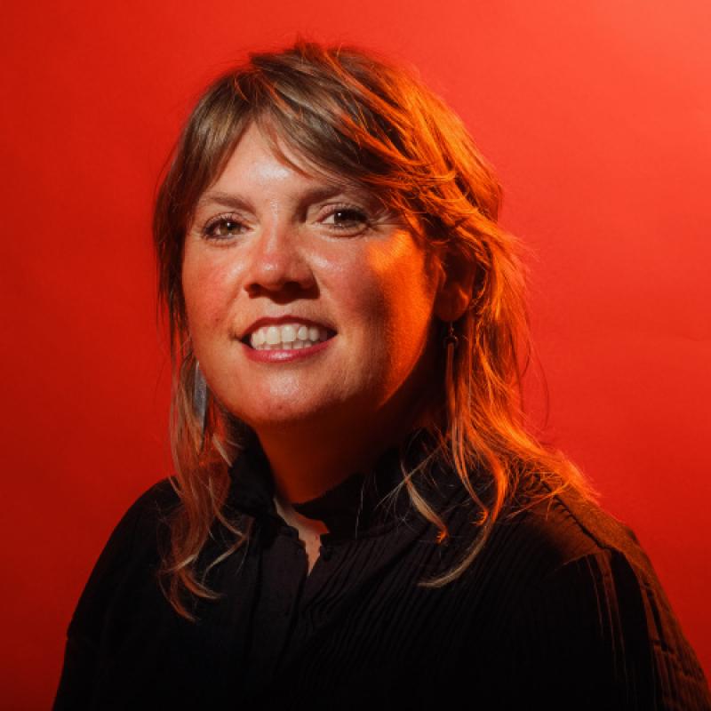 Corine Meijers smiles at the camera. She has long light brown hair and a black top on.