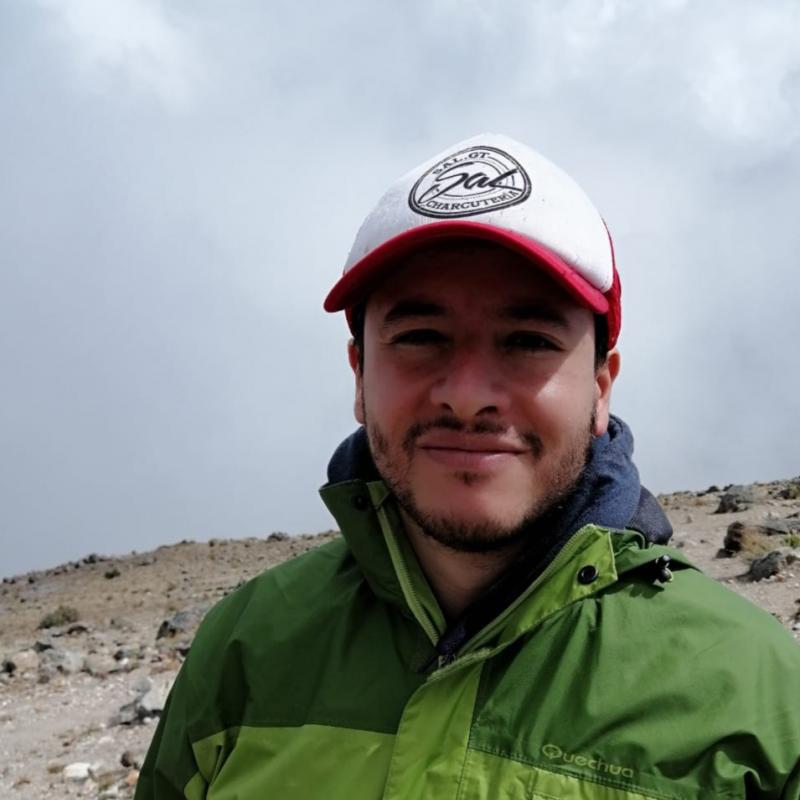 Diego Padilla Vassaux wears a baseball cap and smiles at the camera