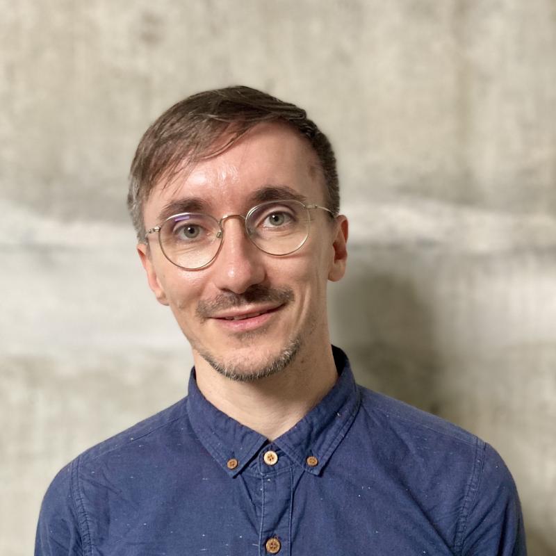 Nico Unterman smiles at the camera. He wears a blue shirt and short brown hair.