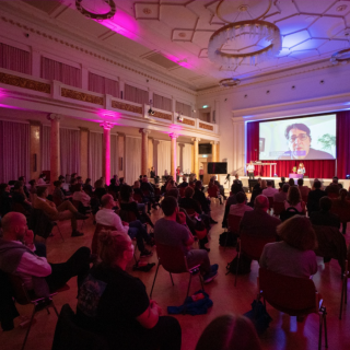 SILBERSALZ Awards ceremony. A crowd is seated in front of a screen where a winner accepts their award virtually.