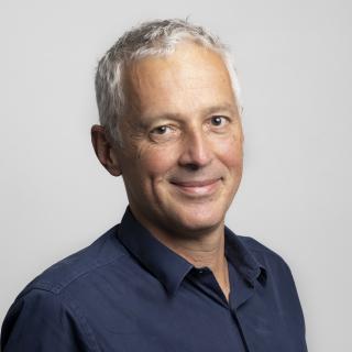 Alain Chetodal smiles at the camera. He has white hair and a blue shirt.